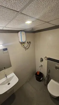 a bathroom with a white toilet and a sink at Aaram Miraj Luxuria Apartment -1 in Wayanad