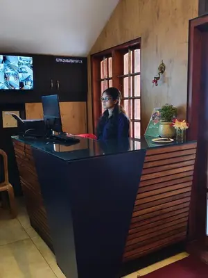 a woman sitting at a counter with a laptop at Hotel Orchard Coorg in Virajpet