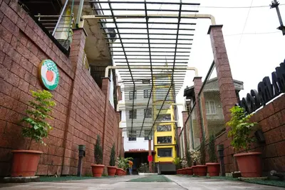 a building with awning over a street with plants at Hotel Orchard Coorg in Virajpet