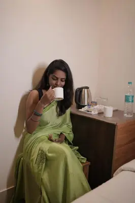 a woman in a green dress drinking from a coffee cup at Hotel Orchard Coorg in Virajpet