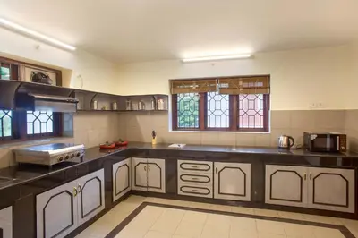 a large kitchen with black counter tops and windows at Away From Home - 2 - Rooms In Ooty, Home Stay Ooty in Ooty