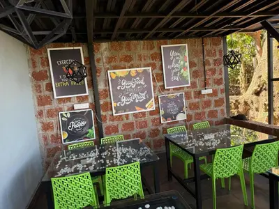 a brick wall with a table and chairs and signs at The Cozy Clouds Hill Saty in Madikeri