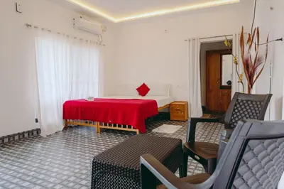 a room with a bed with a red table and chairs at Lilliput Haven Homestay in Sultan Bathery