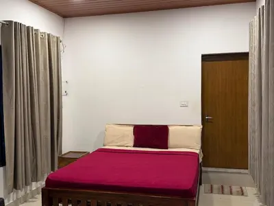 a bedroom with a bed with a red blanket at Lilliput Haven Homestay in Sultan Bathery