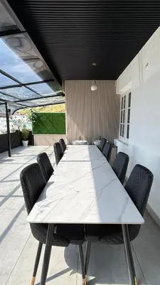 a large white table with chairs on a patio at Leafy Mist Villa in Munnar