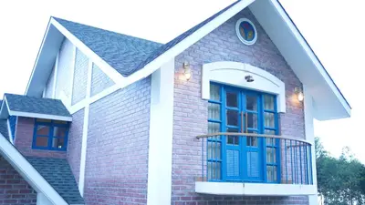 a house with a blue door and a balcony at Preserve Ooty in Ooty