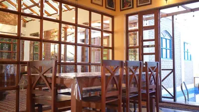 a dining room with a table and chairs and windows at Preserve Ooty in Ooty