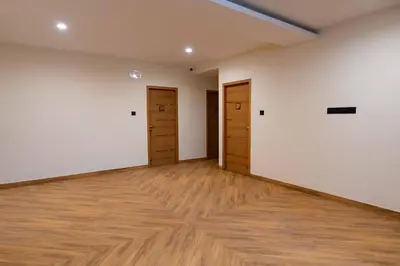 an empty room with two doors and wood floors at The Paradise International Hotel in Coimbatore
