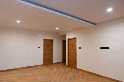 an empty room with two doors and wood floors at The Paradise International Hotel in Coimbatore