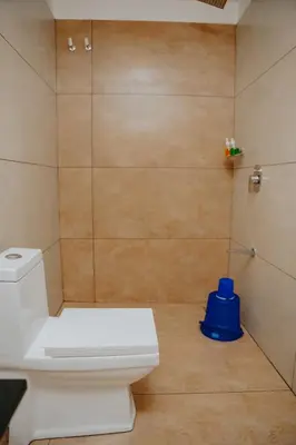 a bathroom with a toilet and a blue stool at Saj Heritage in Kalpetta