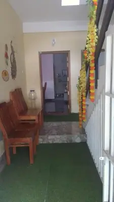 a living room with a staircase with a chair and a room with green carpet at Stay Castle in Guruvāyūr