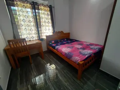 a bedroom with a bed and a chair and a window at Stay Castle in Guruvāyūr