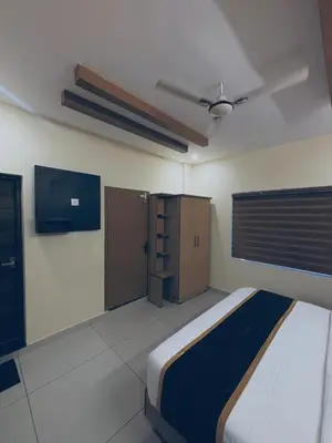 a bedroom with a bed and a cabinet in it at Azay Luxurious Apartment in Kalpetta