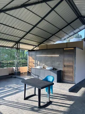 a patio with a table and a kitchen at Azay Luxurious Apartment in Kalpetta