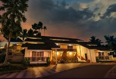 a building with a palm tree in front of it at Holidays Garden Resort in Kalpetta