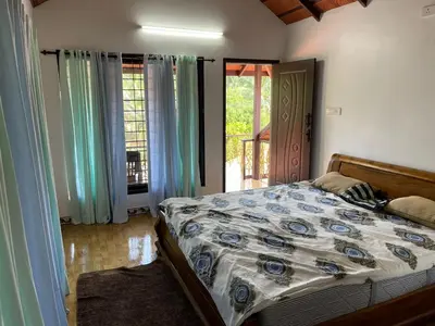 a bedroom with a bed and a door to a balcony at Yes Yes Farms in Pollāchi