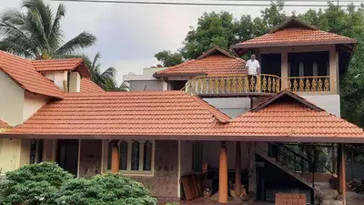 a man standing on the balcony of a house at Yes Yes Farms in Pollāchi