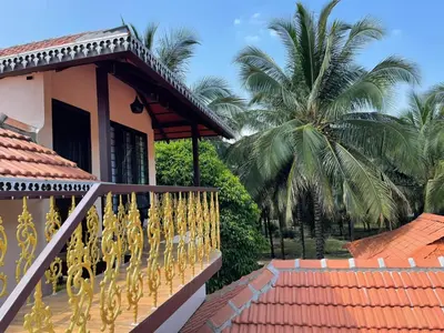 a balcony of a house with palm trees in the background at Yes Yes Farms in Pollāchi