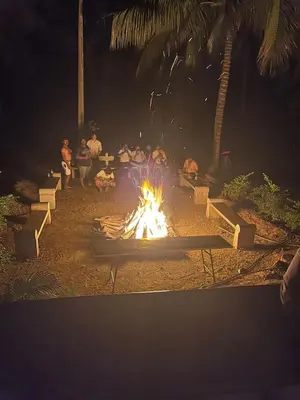 a fire pit with people sitting around it at night at Yes Yes Farms in Pollāchi
