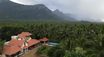 an aerial view of a resort with palm trees and mountains at Yes Yes Farms in Pollāchi