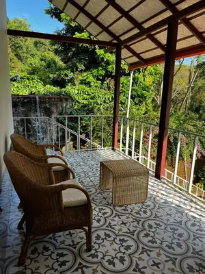 a porch with two chairs and a table on a patio at Birdsong Coffee Estate Stay in Madikeri
