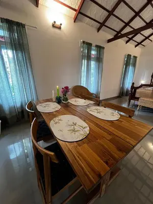 a wooden table with plates on it in a living room at Birdsong Coffee Estate Stay in Madikeri