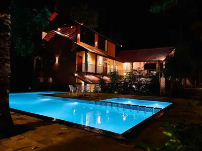 a swimming pool in front of a house at night at Athirapilly Ontherocks in Athirappilly