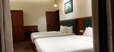 two beds in a hotel room with white sheets at Athirapilly Ontherocks in Athirappilly