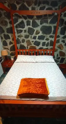 a bed with a wooden headboard with a blanket on it at WellGrown- The Farmhouse at Kombai - Pallangi, Kodaikanal in Kodaikānāl