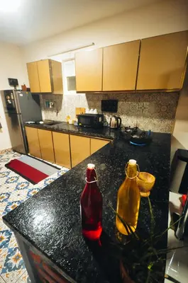 a kitchen with a black counter with two bottles on it at WellGrown- The Farmhouse at Kombai - Pallangi, Kodaikanal in Kodaikānāl