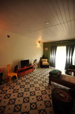 a living room with a couch and a tv at WellGrown- The Farmhouse at Kombai - Pallangi, Kodaikanal in Kodaikānāl