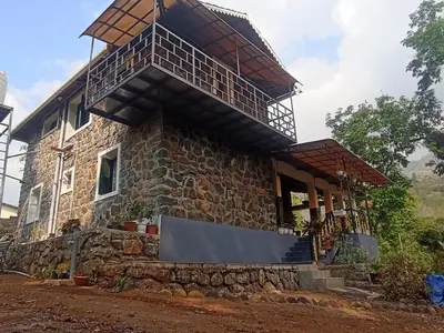 a stone house with a balcony on top of it at WellGrown- The Farmhouse at Kombai - Pallangi, Kodaikanal in Kodaikānāl