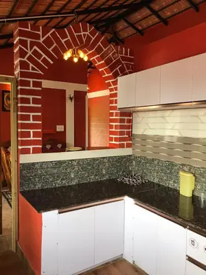 a kitchen with white cabinets and a brick wall at Snow Drop Villa in Gonikoppal