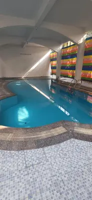 a swimming pool with blue water in a building at Airport villa in Chewarra