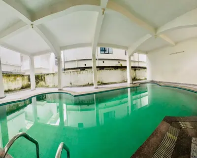 an indoor pool with blue water in a building at Airport villa in Chewarra