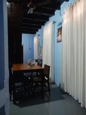 a table and chairs in a room with white curtains at Arapura Veedu Heritage Homestay in Kizhillam