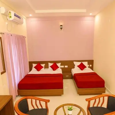 two beds in a room with chairs and a table at Tour Way Nadavayal Inn in Kenichira