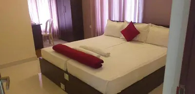 a bedroom with a bed with white and red pillows at Tour Way Nadavayal Inn in Kenichira