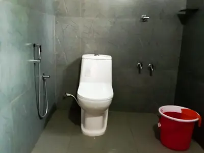 a bathroom with a toilet and a trash can at Aloravillasbooking in Wayanad