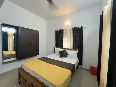 a bedroom with a bed with a yellow blanket at Aloravillasbooking in Wayanad
