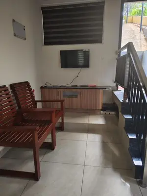 a living room with a chair and a flat screen tv at Aloravillasbooking in Wayanad