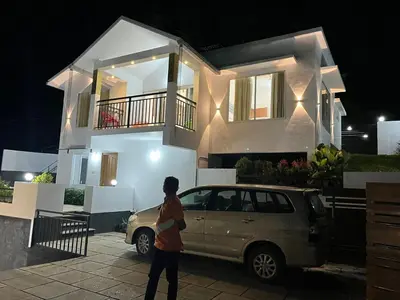 a person walking in front of a house with a car at Aloravillasbooking in Wayanad