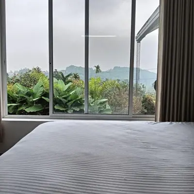 a bedroom with a bed and a large window with a view at Aloravillasbooking in Wayanad