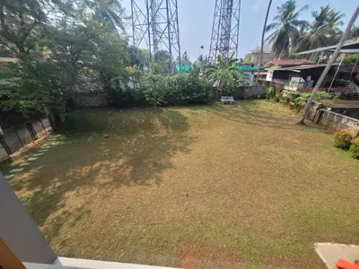 a large yard with grass and trees and a fence at Aurora The Pool Villa in Kozhikode