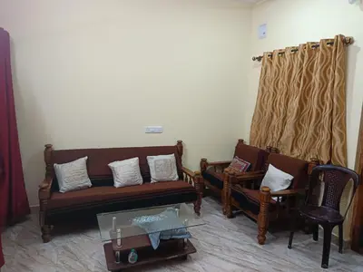 a living room with couches and chairs and a table at Holy Family Nest in Mysore