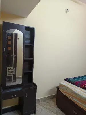 a mirror on a dresser next to a bed at Holy Family Nest in Mysore