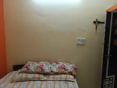 a bedroom with a bed and a cross on the wall at Holy Family Nest in Mysore