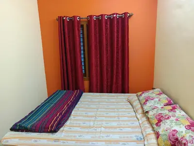 a bed in a room with red curtains at Holy Family Nest in Mysore