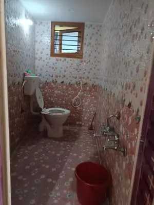 a small bathroom with a toilet and a window at Holy Family Nest in Mysore