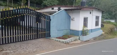 a fence with christmas lights on it next to a house at Varshinicottage kothkiri in Kotagiri